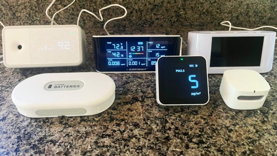 Comparison of Indoor Air Quality Monitor there are different devices laying in table with there wires and with digital screen 