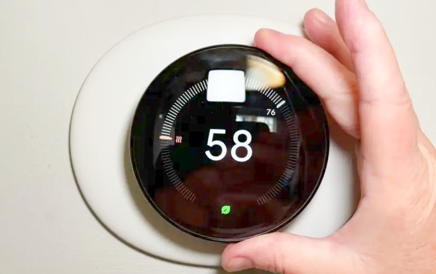 a men holds Nest Learning Thermostat in black color and its temperature is 58